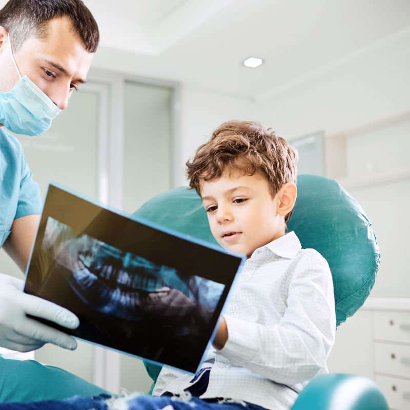 2 a pediatric dentist showing his patient his teeth X-rays